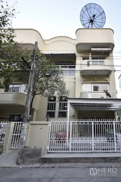 Townhouse for rent in Wang Thonglang, Bangkok - Three-storey townhouse exterior with balconies, gated carport and satellite dish in Bangkok.