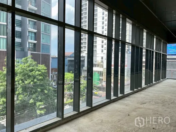 พื้นที่ขายปลีก ให้เช่า - แนวกระจกเต็มความสูงทอดยาว มองเห็นต้นไม้และตึกสูง