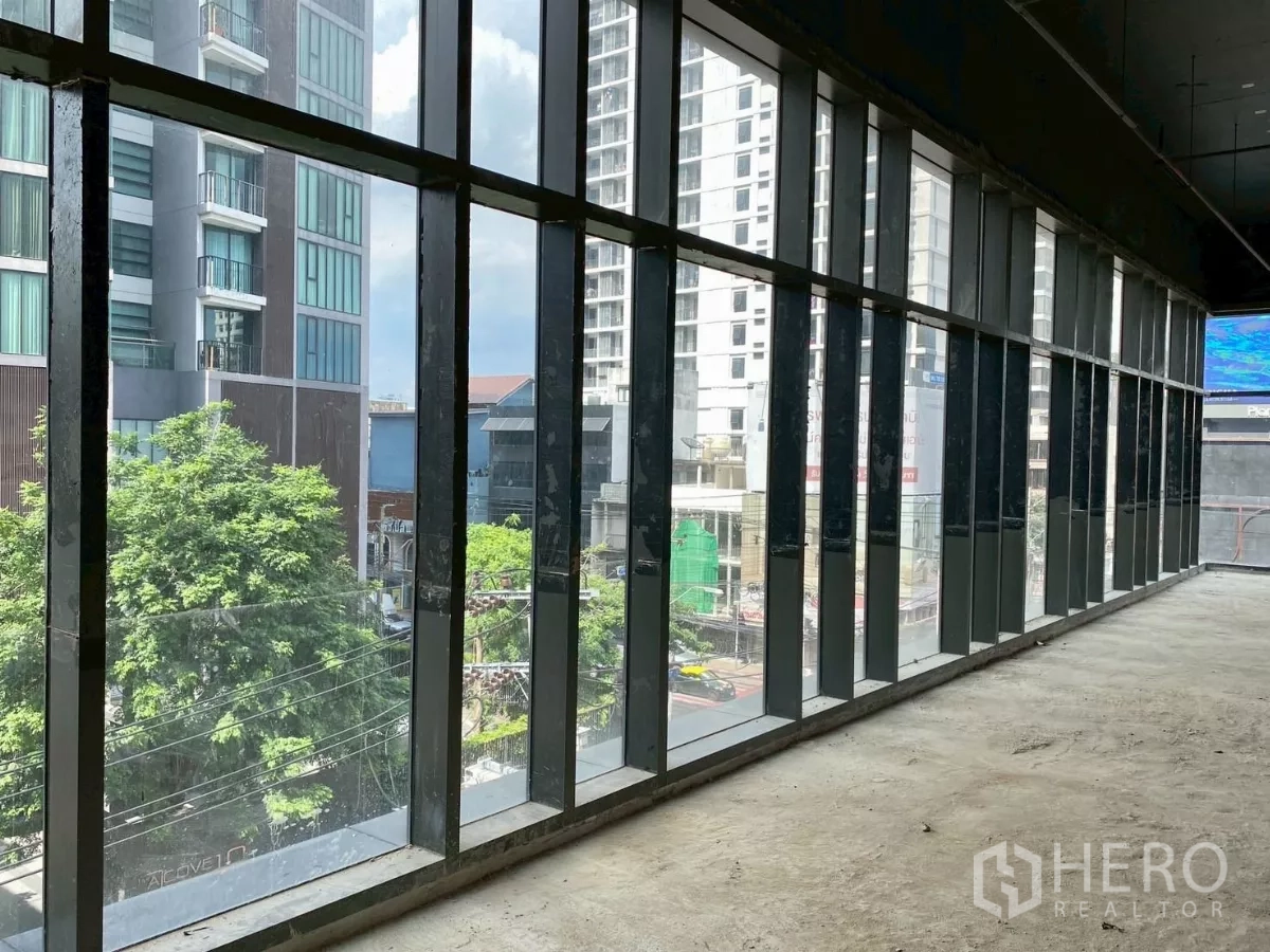 พื้นที่ขายปลีก ให้เช่า - แนวกระจกเต็มความสูงทอดยาว มองเห็นต้นไม้และตึกสูง