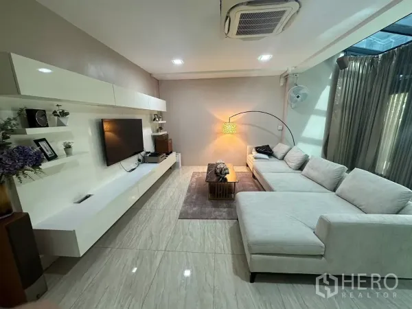 บ้าน ให้เช่าหรือขายในBang Kapi, Bangkok - ห้องนั่งเล่นโมเดิร์น โซฟา L‑shape ผนังทีวีบิวท์อิน และพื้นกระเบื้องเงา