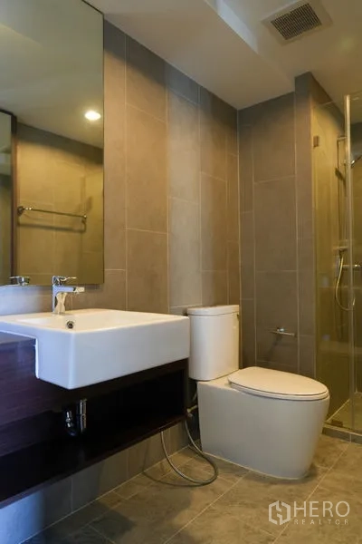 Condominium for sale in Watthana, Bangkok - Modern bathroom featuring a glass-enclosed shower, square vanity and neutral tiles.