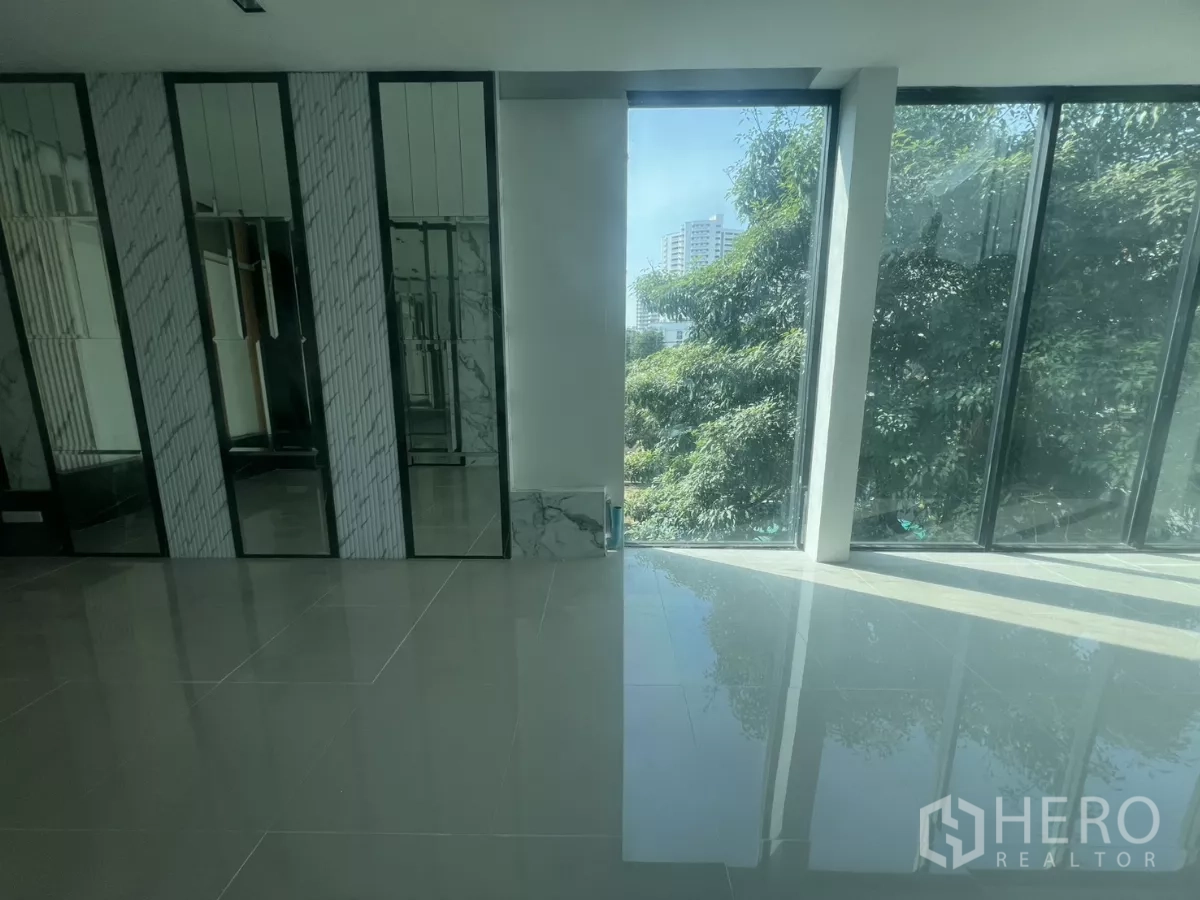 零售空间 出租在Watthana, Bangkok - 明亮室内，亮面瓷砖地、镜面装饰墙与落地窗，可见城市与树景。