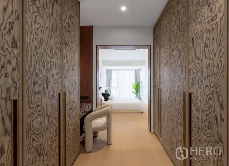 Townhouse for sale in Sathon, Bangkok - Walk-in closet corridor with patterned wooden wardrobes leading to the bedroom.