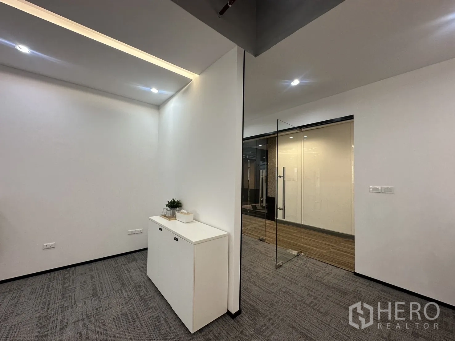 办公室 for rent in Pathum Wan, Bangkok - 接待角落设白色柜体、筒灯照明与透明玻璃门入口。