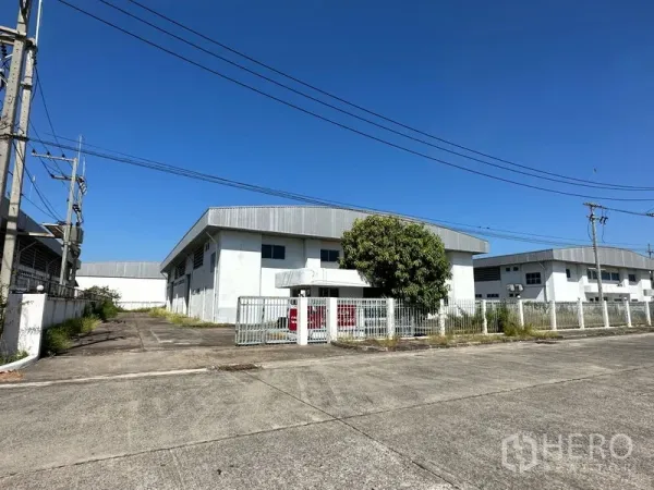 โรงงาน ให้เช่าในChon Buri - โรงงานสีขาวพร้อมรั้วและทางเข้าออกกว้าง ตั้งอยู่ในโซนอุตสาหกรรม ใต้ท้องฟ้าสดใส