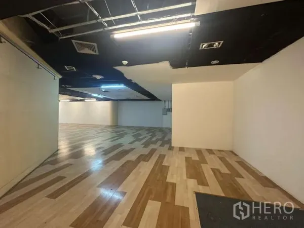 零售空间 出租 - 无柱销售大厅，木纹地面与外露顶面机电设施。