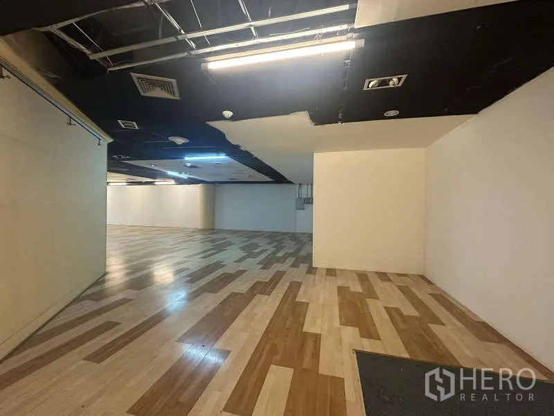 零售空间 出租 - 无柱销售大厅，木纹地面与外露顶面机电设施。