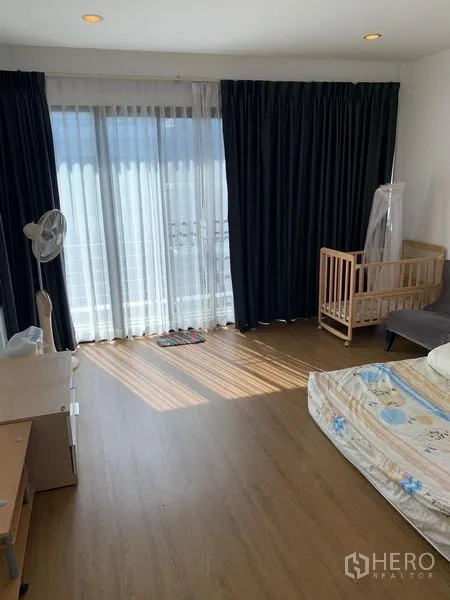 Office Space for sale in Saphan Sung, Bangkok - Spacious room with wood flooring, floor-to-ceiling curtains and balcony doors.