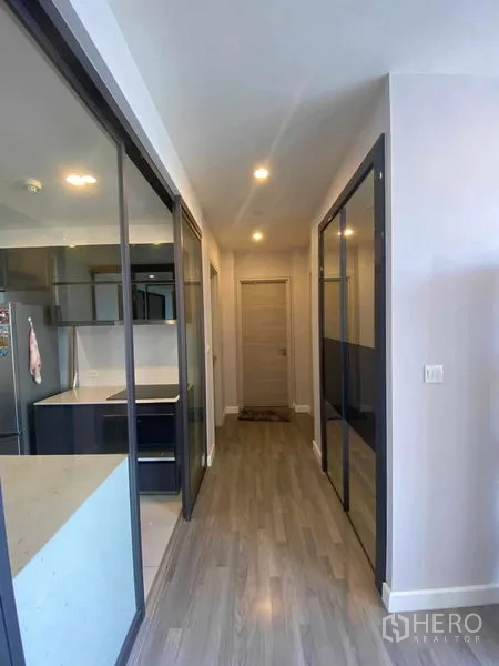 คอนโด ให้เช่าหรือขายในBang Rak, Bangkok - โถงทางเดินพร้อมฉากกั้นกระจกบานเลื่อนและพื้นไม้ไปยังห้องต่างๆ