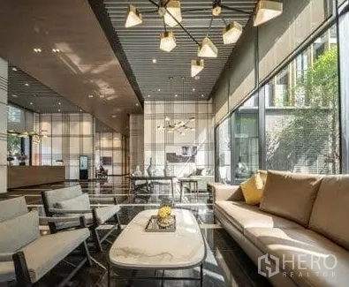 Condominium for rent in Watthana, Bangkok - Hotel‑style lobby lounge with contemporary chandelier, sofas and floor‑to‑ceiling windows.