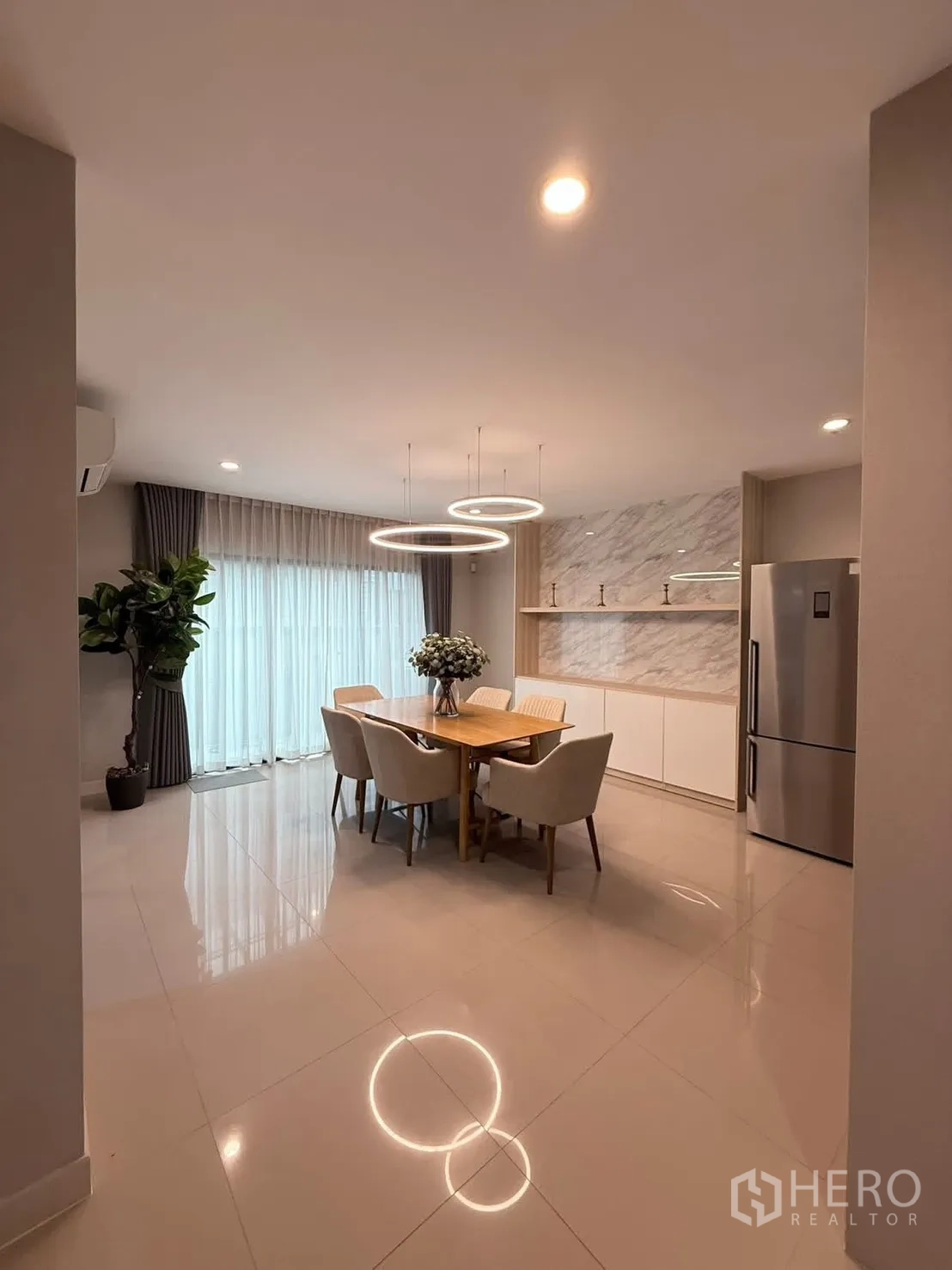 Townhouse for rent in Saphan Sung, Bangkok - Dining area with circular LED chandeliers, six chairs and tall curtains.