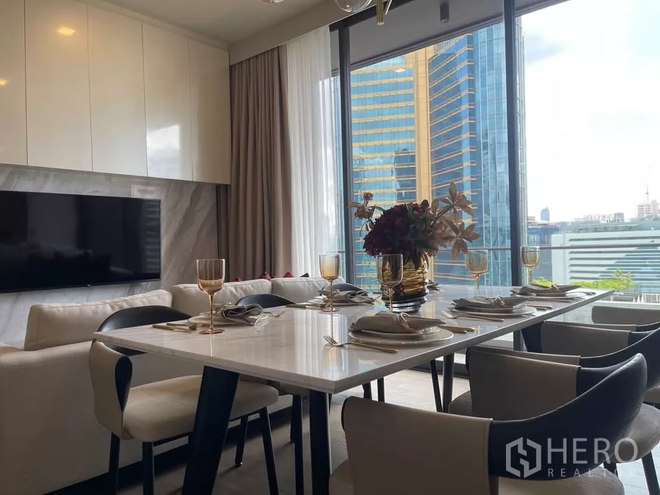 Condominium for rent in Watthana, Bangkok - Dining space by full-height windows with skyline view and elegant table setting.