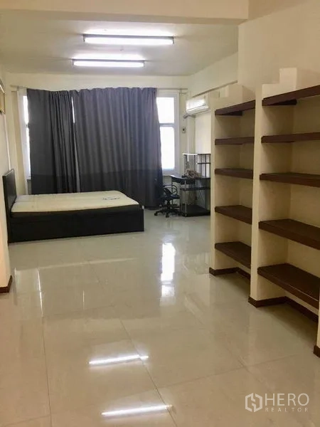 อาคารพาณิชย์ ให้เช่าในSuan Luang, Bangkok - ห้องสตูดิโอกว้าง ปูกระเบื้อง มีชั้นวาง เตียง โต๊ะทำงาน และเครื่องปรับอากาศ