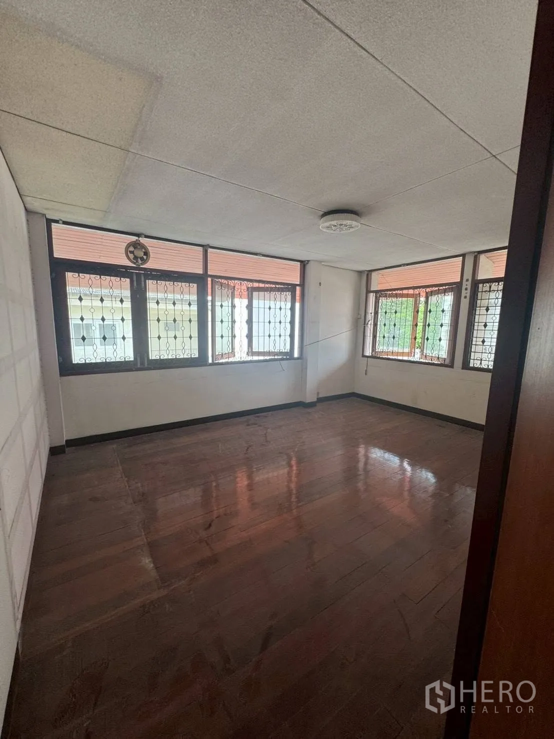 Detached House for rent or sale in Watthana, Bangkok - Upper room with polished wood floor and windows fitted with security grilles.