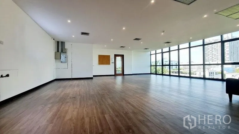 Office Space for rent in Watthana, Bangkok - Large open-plan office with wood-look flooring, recessed lighting and floor-to-ceiling windows.