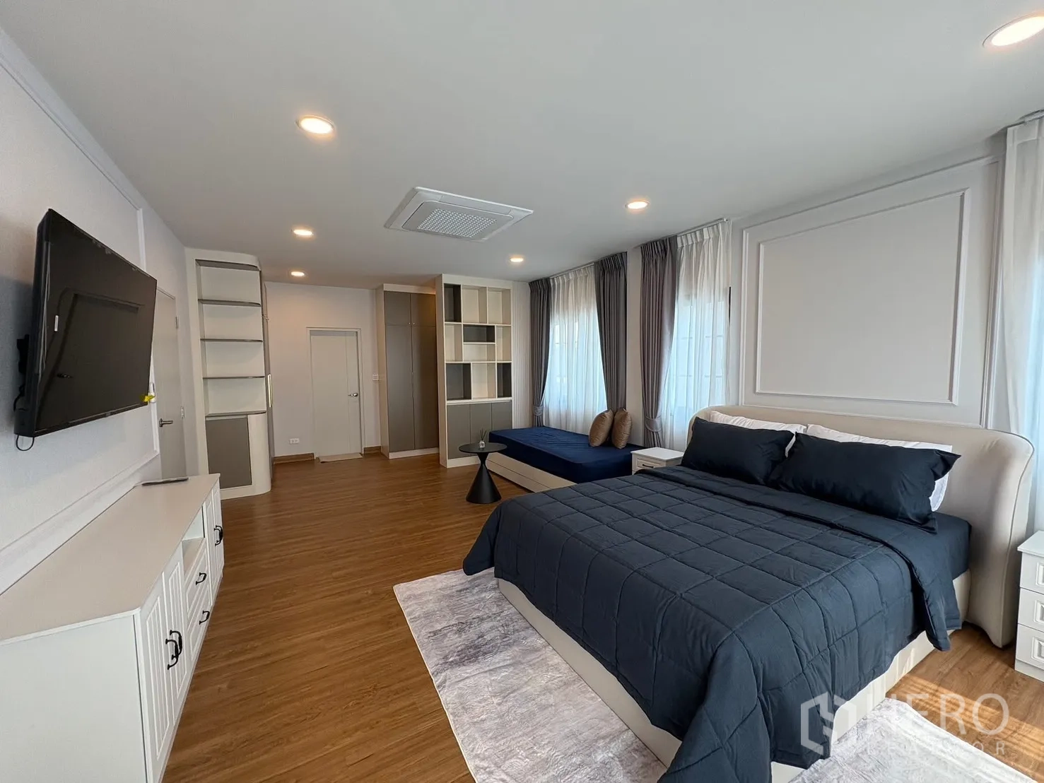 Detached House for rent in Bang Phli, Samut Prakan - Master suite angle showing TV cabinet, shelving and bed over wood flooring.