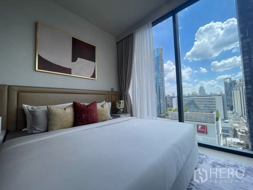 Condominium for rent in Watthana, Bangkok - Master bedroom with king bed and floor-to-ceiling corner windows overlooking Asoke skyline.