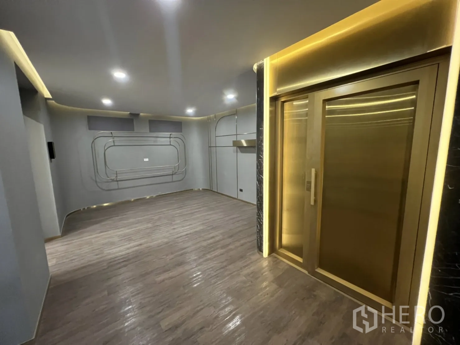 店屋 出租在Phra Khanong, Bangkok - 电梯前厅，金色门框与木纹地面。