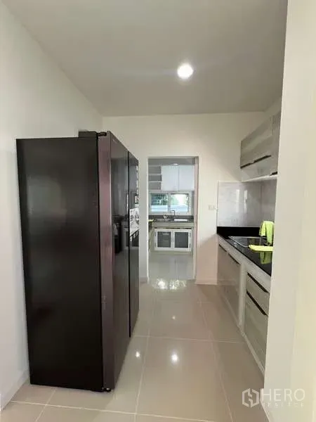 บ้าน ให้เช่าในBang Kapi, Bangkok - ครัวแบบแกลเลย์พร้อมตู้เย็นสีดำสูงและตู้บิลต์อิน เชื่อมต่อครัวไทย