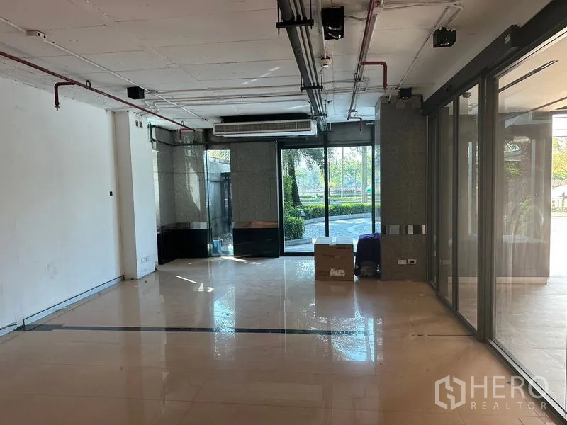 สำนักงาน ให้เช่าในKhlong Toei, Bangkok - พื้นที่ออฟฟิศแบบโอเพ่นสเปซ พื้นกระเบื้องเงา เพดานโชว์งานระบบ และประตูกระจกมองเห็นสวน