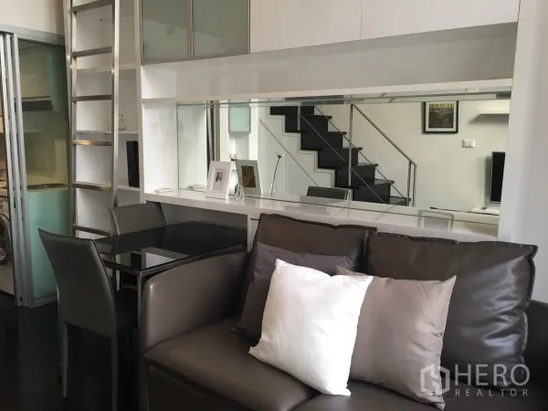 คอนโด ให้เช่าในKhlong Toei, Bangkok - โซนนั่งเล่นโมเดิร์น โซฟาหนัง โต๊ะกินข้าวกระจก ผนังกระจกเงาพร้อมตู้บิลท์อิน และประตูกระจกสไลด์ไปครัว