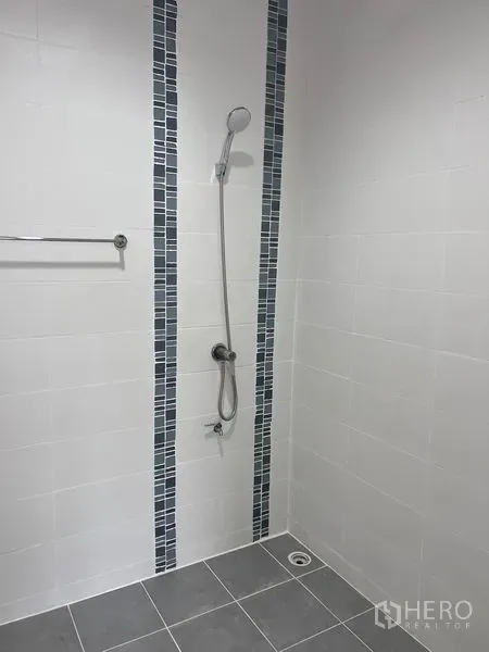 Home Office for sale in Lat Krabang, Bangkok - Walk-in shower area tiled in white with vertical blue mosaic strips and handheld shower.