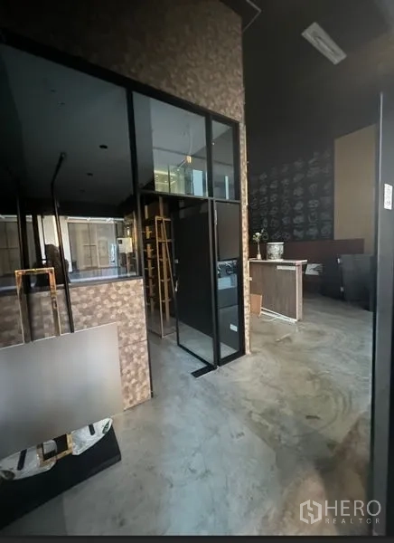 零售空间 出租在Watthana, Bangkok - 店铺内部带玻璃隔断、水泥地面与服务台。