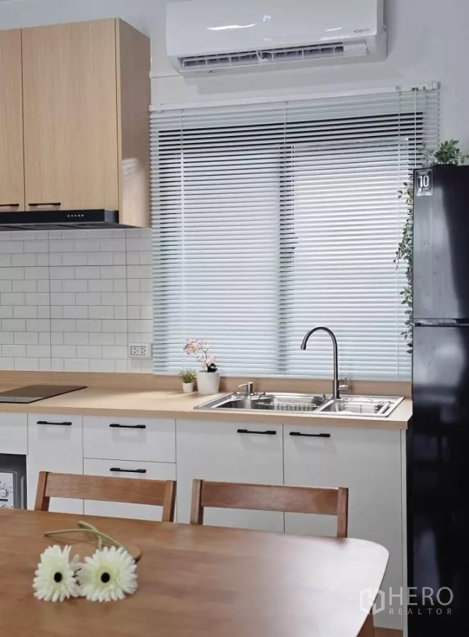 ทาวน์เฮาส์ ให้เช่าในBang Phli, Samut Prakan - ครัวบิลต์อินสว่าง เคาน์เตอร์ไม้ อ่างล้างจานคู่ กระเบื้องซับเวย์ และมู่ลี่หน้าต่าง.