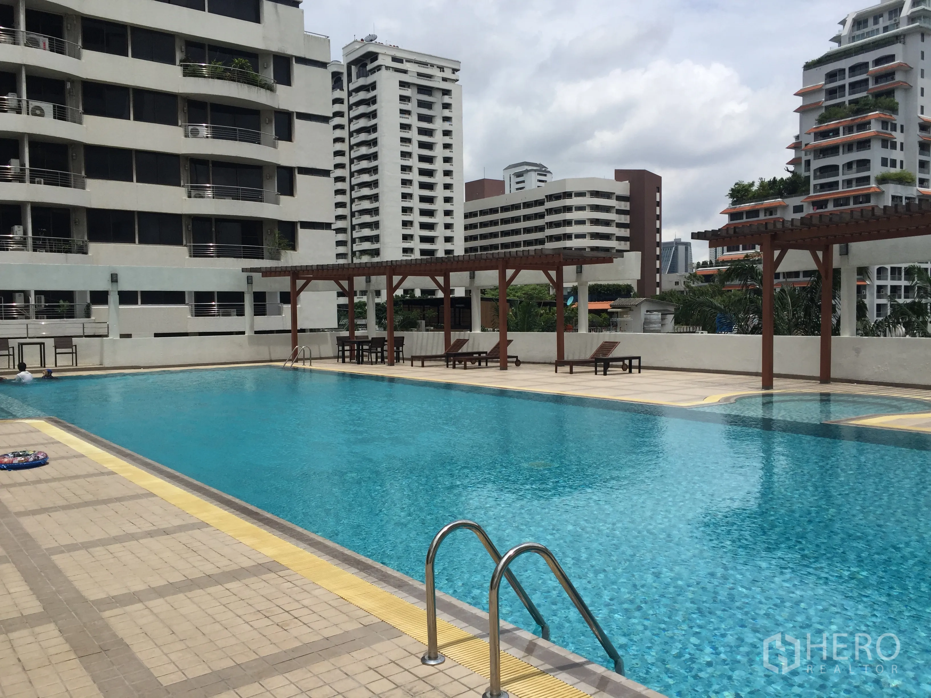 公寓 出售在Watthana, Bangkok - 公寓户外游泳池，设遮阳棚与躺椅，周围高楼林立