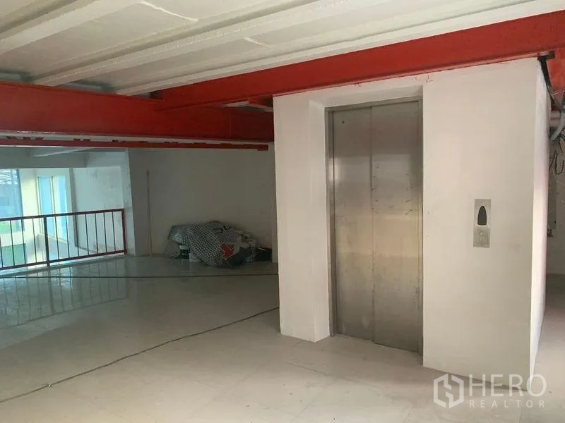 Shophouse for rent in Prawet, Bangkok - Mezzanine level with lift core, red steel structure and polished tiles.