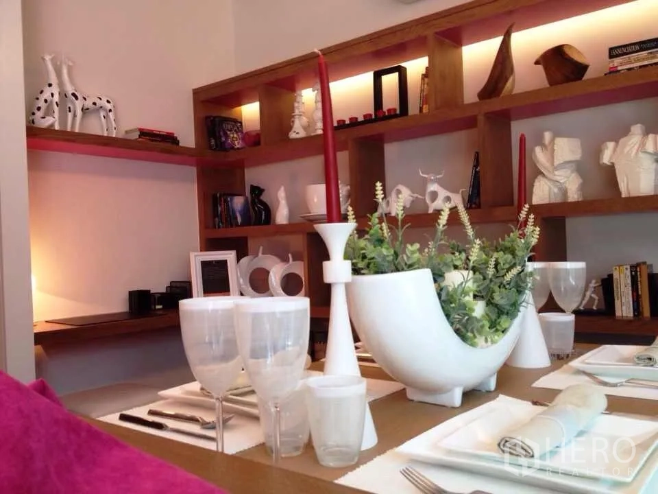 คอนโด ให้เช่าในWatthana, Bangkok - มุมโต๊ะอาหารกับกระถางต้นไม้สี白 เทียนแดง และชั้นไม้มีไฟซ่อนจัดวางงานศิลป์