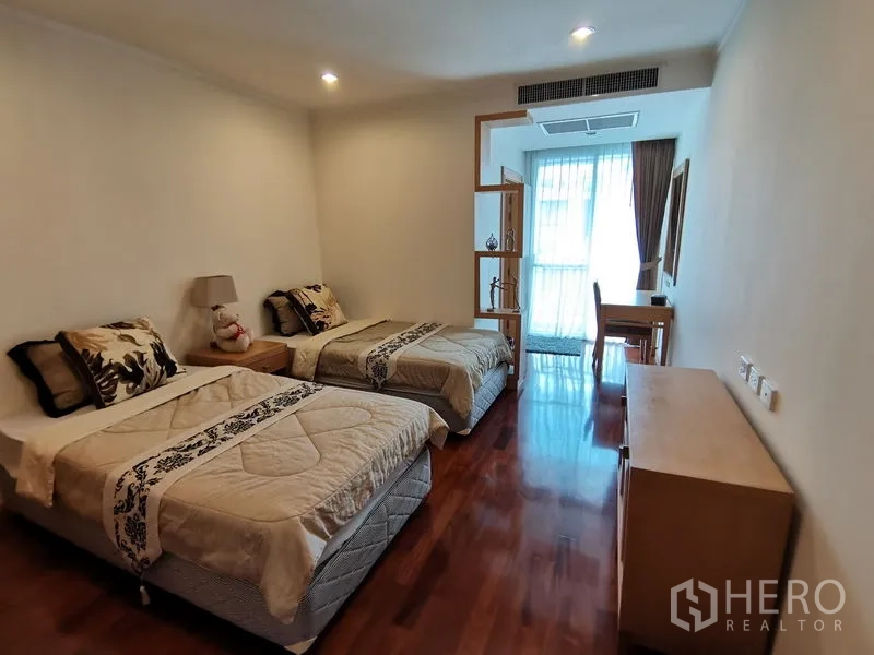 公寓 出租在Khlong Toei, Bangkok - 明亮的双床卧室，木地板，书桌与置物架，通向带薄纱窗帘的阳台门。