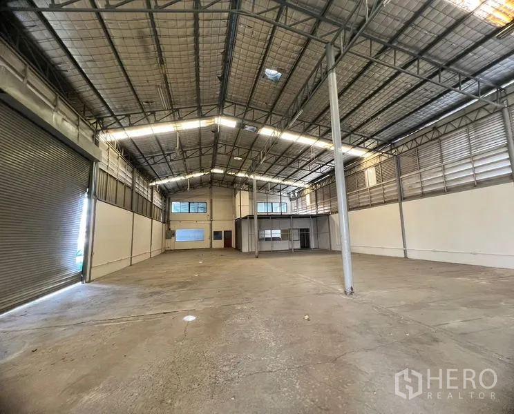 Warehouse for rent in Suan Luang, Bangkok - Main warehouse hall featuring a high insulated roof, concrete floor and wide roller shutter.
