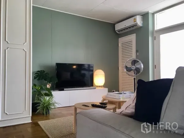 Apartment for rent in Khlong Toei, Bangkok - Media wall with flat-screen TV, console, soft lamp lighting, and air-conditioning in a cozy living zone.