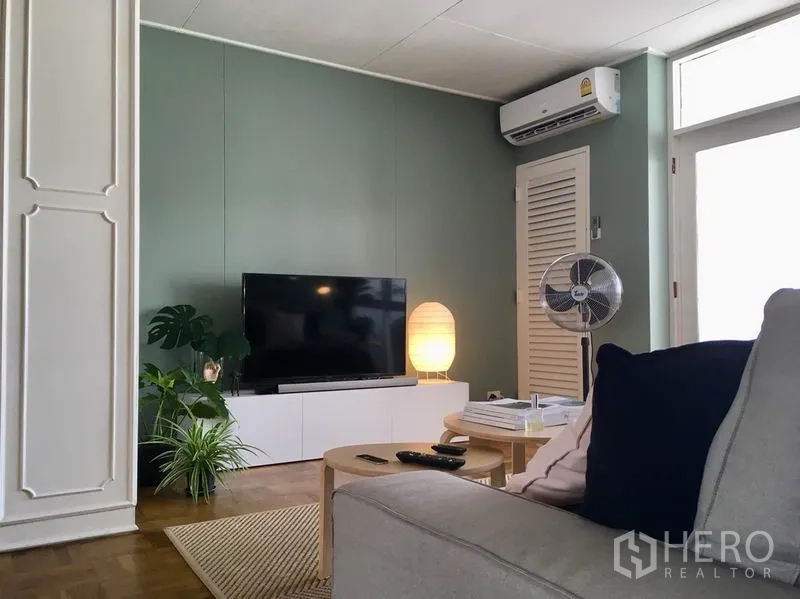 Apartment for rent in Khlong Toei, Bangkok - Media wall with flat-screen TV, console, soft lamp lighting, and air-conditioning in a cozy living zone.