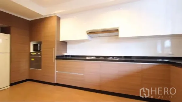 房间 出租在Khlong Toei, Bangkok - 厨房另一视角，内嵌灶台、墙面微波炉与大量柜体。