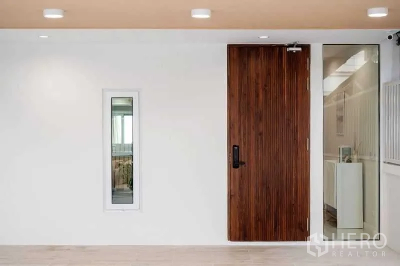 联排别墅 出售在Khlong Toei, Bangkok - 极简入户区，木质入户门、白墙与侧边玻璃，嵌灯照明。