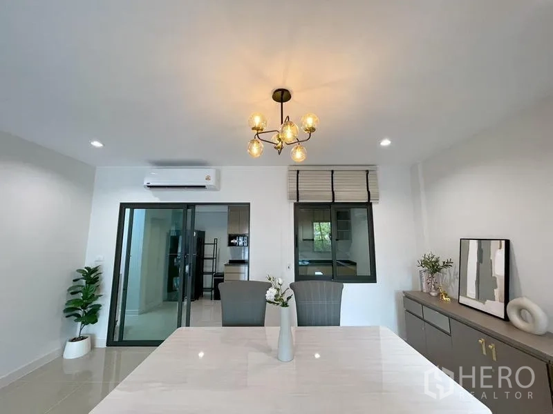 Townhouse for rent in Bang Phli, Samut Prakan - Dining area with chandelier, sideboard and sliding doors to the kitchen.
