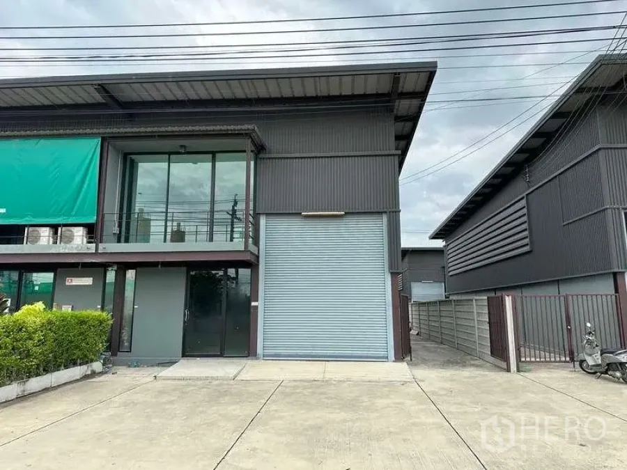 Warehouse for rent in Bang Phli, Samut Prakan - Modern metal-clad warehouse exterior with glass-front office, balcony, and a large roller shutter.