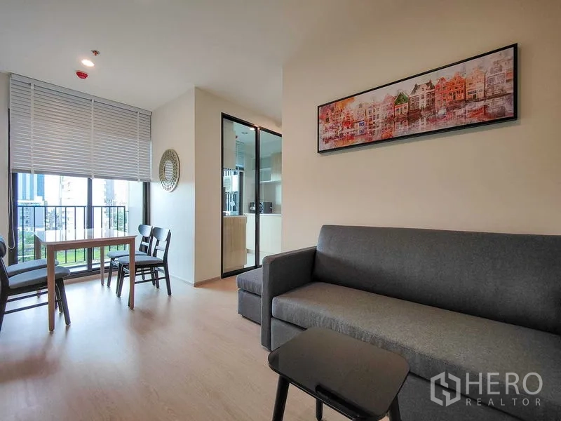 Condominium for rent - Cozy lounge with grey sofa, artwork and sliding door to the separate kitchen.