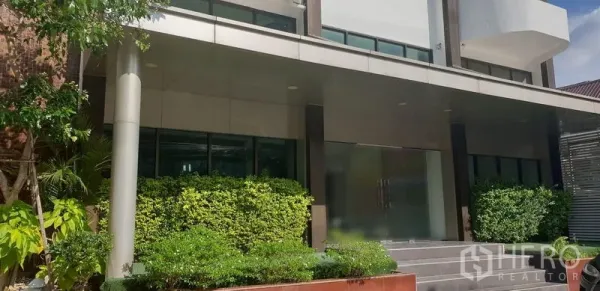 零售空间 出租在Chatuchak, Bangkok - 现代建筑外立面，绿化入口、台阶与宽幅玻璃门面。