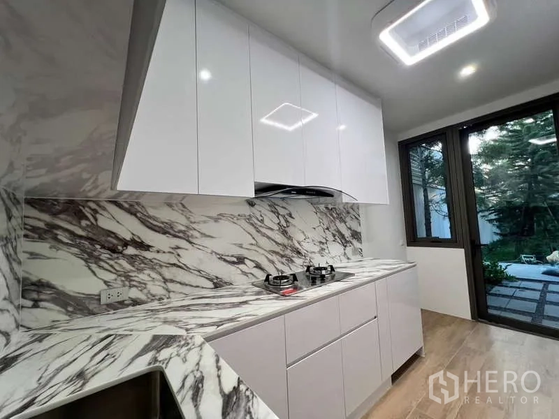 ทาวน์เฮาส์ ให้เช่าในPhra Khanong, Bangkok - ครัวปิดสไตล์โมเดิร์น เคาน์เตอร์ลายหินอ่อน เตาแก๊ส และมุมมองสวน