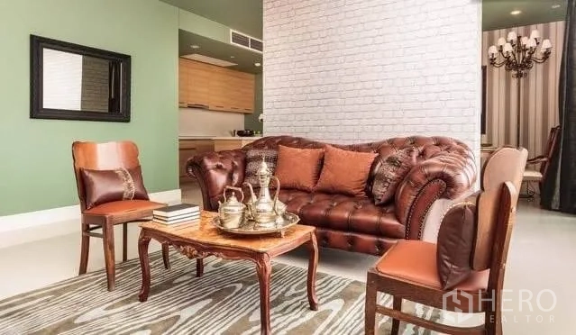 Condominium for rent or sale in Khlong Toei, Bangkok - Cozy living room with leather sofa, vintage chairs, and open-plan layout.