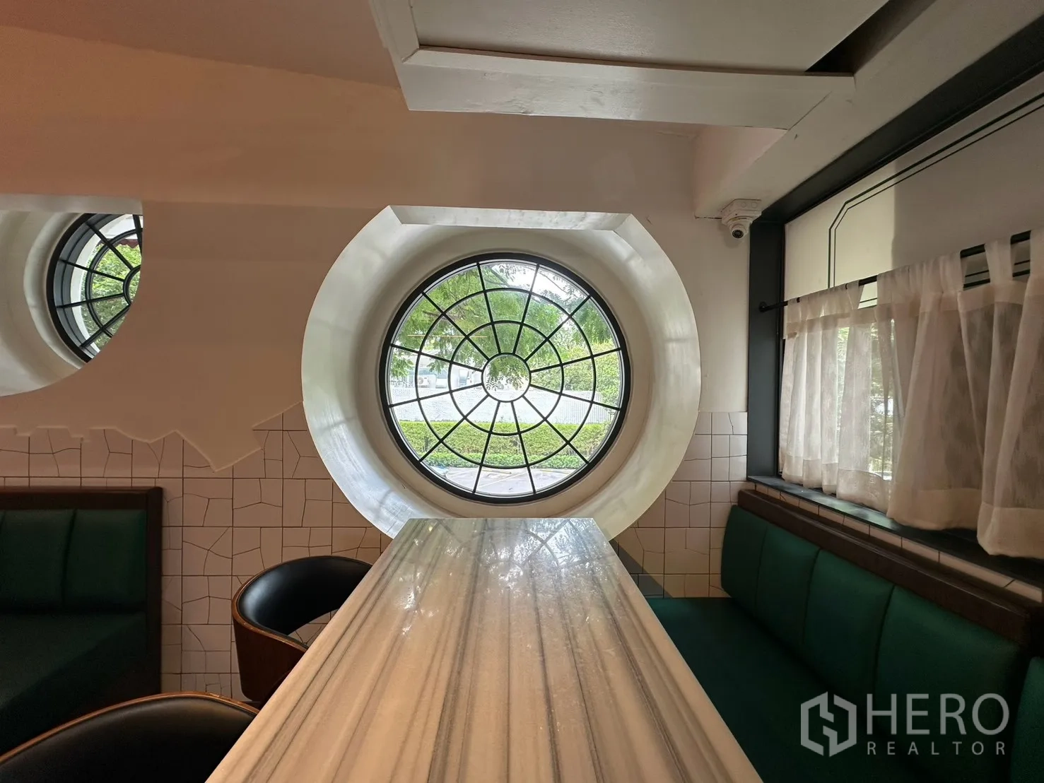 Detached House for rent in Watthana, Bangkok - Close-up of round window beside a booth and stone-pattern tabletop.