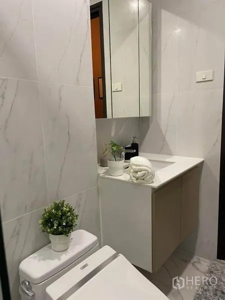 คอนโด ให้เช่าในRatchathewi, Bangkok - มุมอ่างล้างหน้าแบบสว่าง ตู้กระจก และต้นไม้กระถางในห้องน้ำลายหินอ่อน