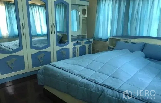 Detached House for rent in Khlong Sam Wa, Bangkok - Second bedroom with blue built-in wardrobe, dressing table and matching curtains.