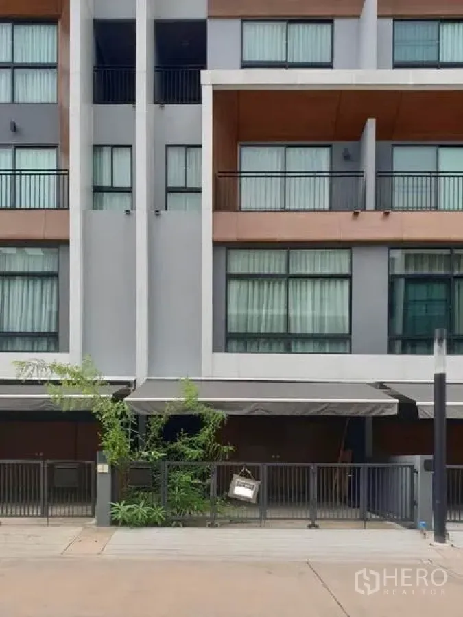 Townhouse for rent in Suan Luang, Bangkok - Modern Bangkok townhouse exterior with balconies, wide windows and gated parking.