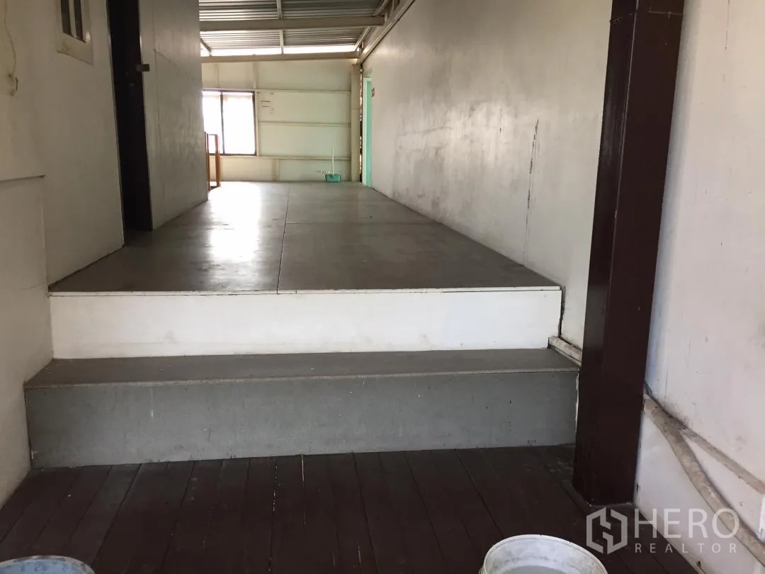 Home Office for rent or sale in Bang Khun Thian, Bangkok - Short steps leading to a raised work platform in the warehouse-style zone.