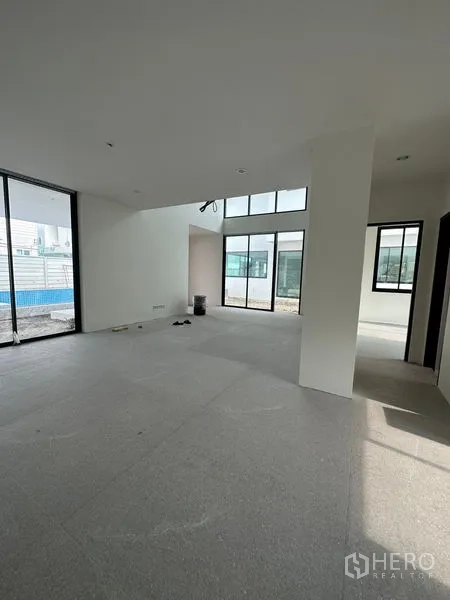 独立式住宅 出租在Watthana, Bangkok - 宽敞起居区，大片窗户和推拉门面向庭院与泳池区。