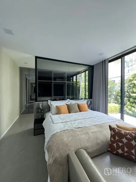 Detached House for rent in Saphan Sung, Bangkok - Ground-floor bedroom with glass partition and garden views through tall windows.